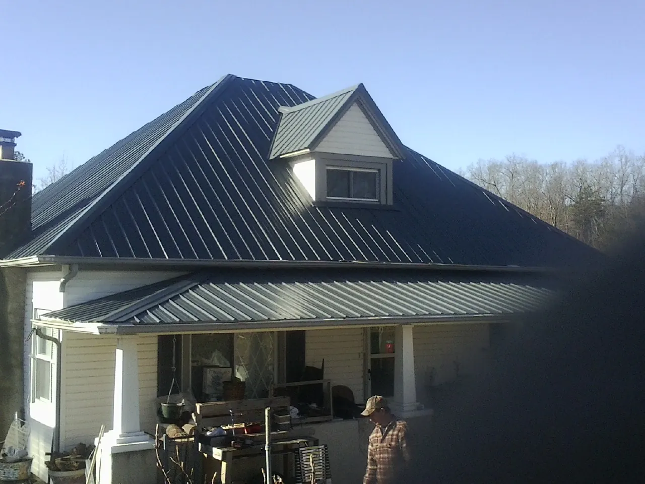 Dark blue standing seam metal roof with a dormer above a front porch in Norris